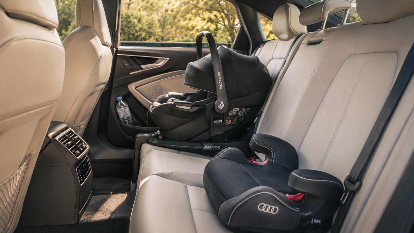 ear-facing baby seat and booster fitted in rear of Audi A6 taxi interior   