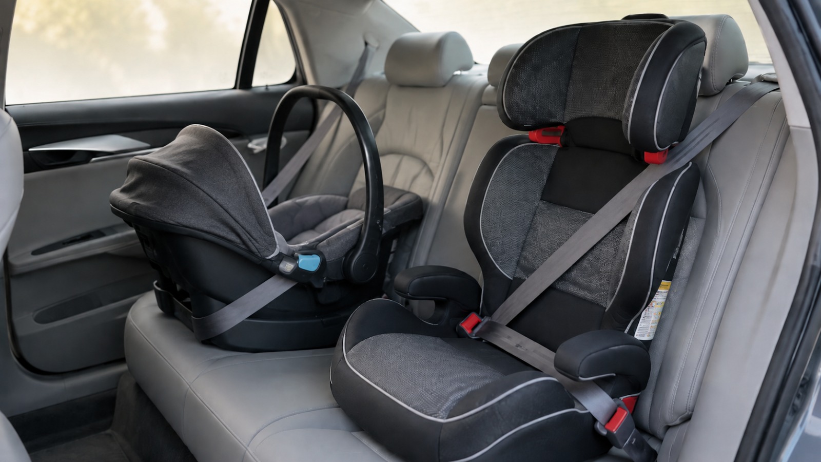 Two child car seats fitted side by side across the rear bench of a saloon